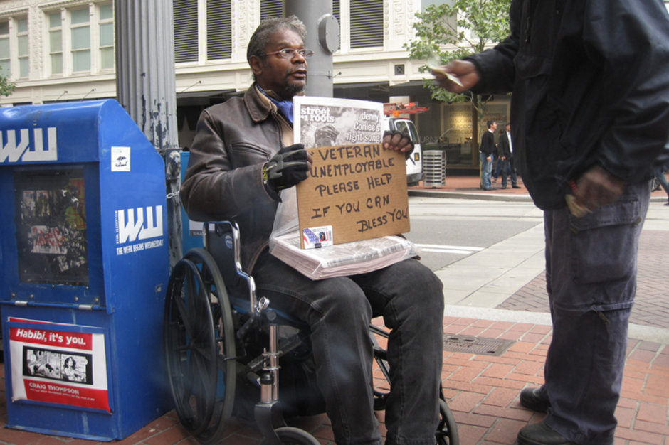 Homeless man in wheelchair holding sign saying 